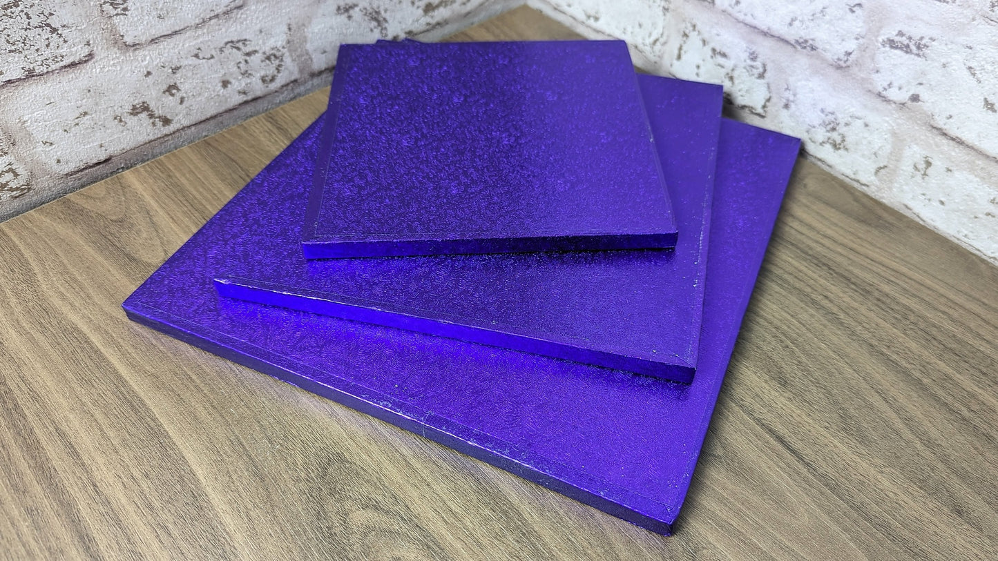 Stacked square purple cake drums made of compressed cardboard with a foil covering