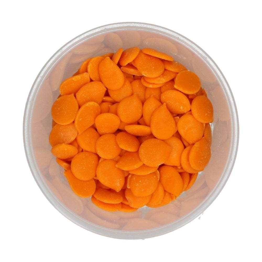 Clear container filled with orange round wilton candy melts on a white background