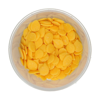 Clear container filled with yellow round wilton candy melts on a white background